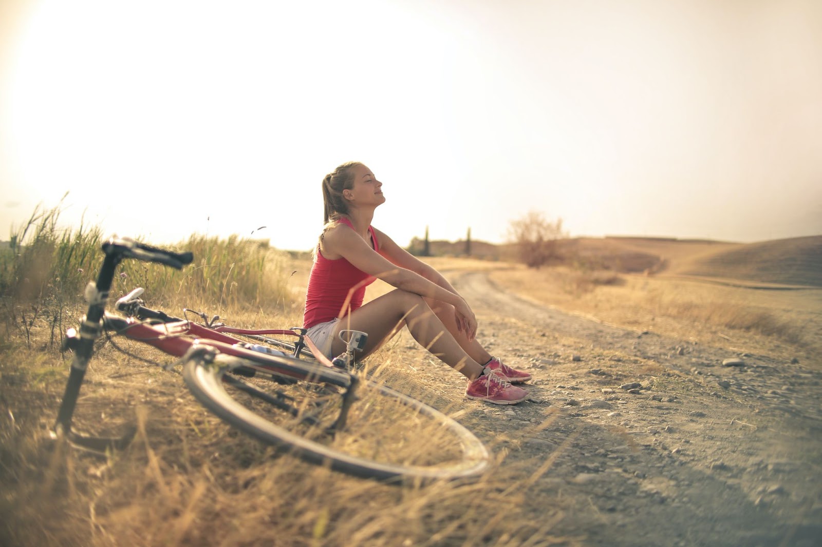 Female student sitting in field with bike