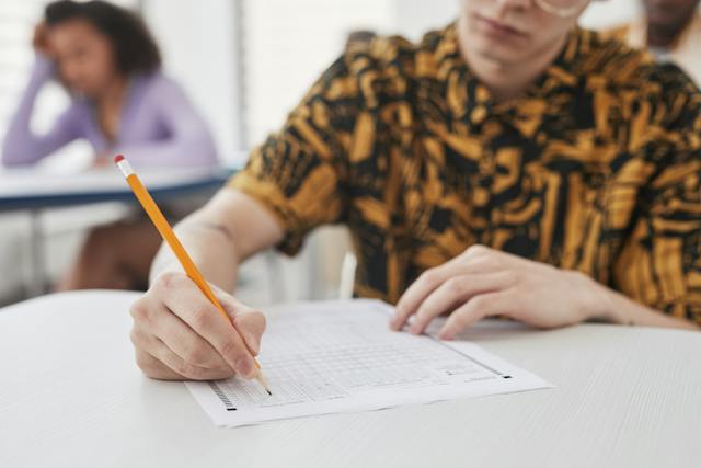 male student writing test in classroom