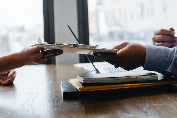 person handing clipboard to other person