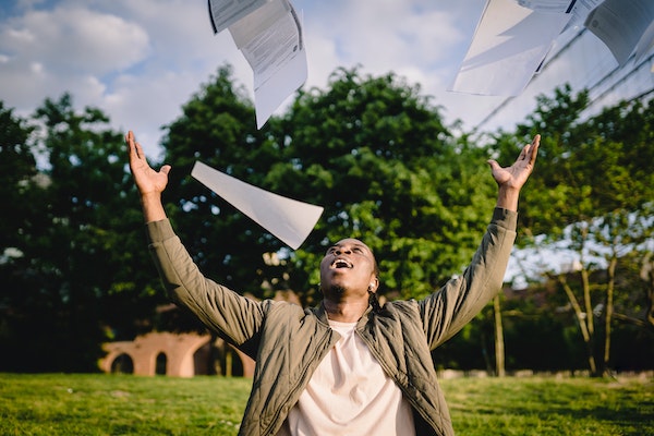 male student throwing papers in air